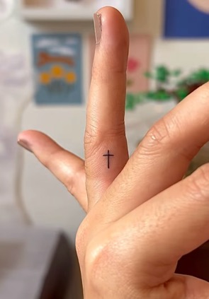 Tiny cross finger tattoo